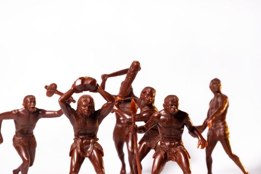 Large toy figures of primitive people on a white background.
