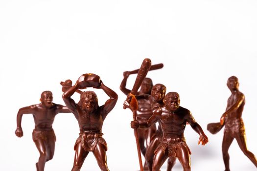 Large toy figures of primitive people on a white background.