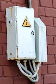 Metal box with wires on a brick wall close up