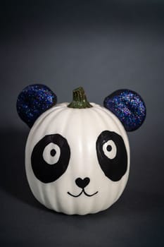 Panda pumpkin with glittery ears for Halloween on a black background.