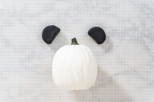 Flat lay. Making ears from black clay to make panda pumpkin for Halloween.