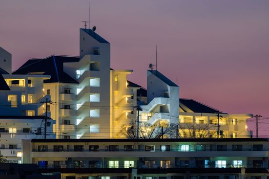 Modern apartment buildings lit with blue hour glow in sky. High quality photo