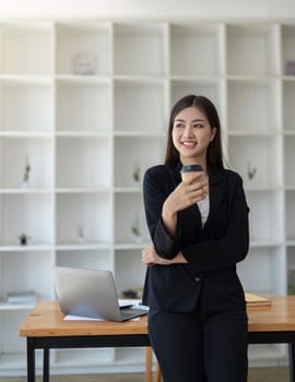 Young minded successful employee business woman work hold cup coffee to stand at desk with laptop pc computer at office Achievement career concept.