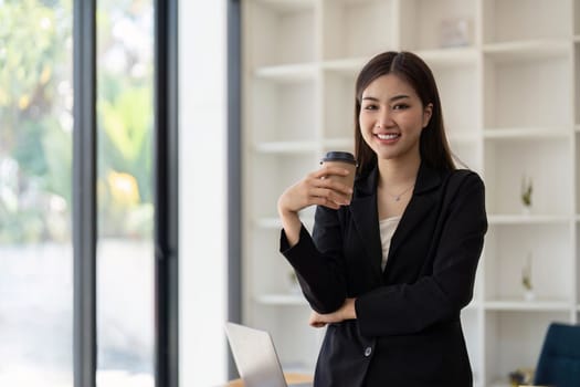 Young minded successful employee business woman work hold cup coffee to stand at desk with laptop pc computer at office Achievement career concept.