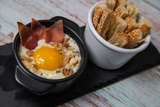 Recipe Oeuf cocotte with fresh cream sauce, Roquefort and walnuts, ham chips, toasted bread sticks. High quality photo
