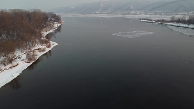 Winter unfrozen river view from above. Snow lies on the island. Drone view. 4k