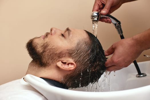 Barber washing hair of caucasian man in barber shop