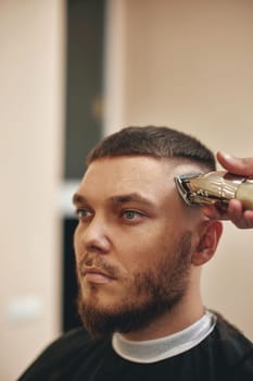 Barber shaving handsome bearded man in barber shop.