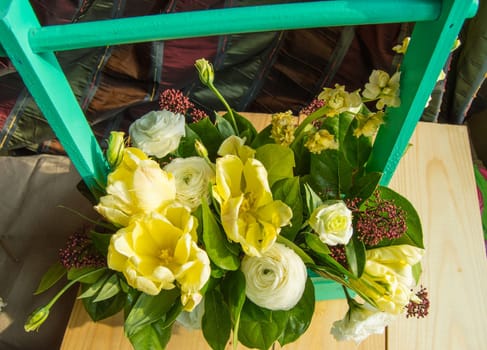 Spring flower arrangement in a green wooden box with a crossbar