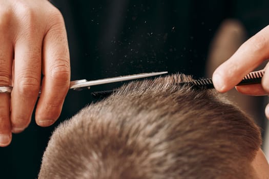 master hairdresser does hairstyle with scissors and comb. close-up
