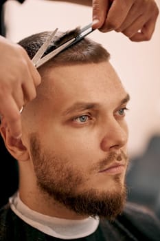 master hairdresser does hairstyle with scissors and comb. close-up