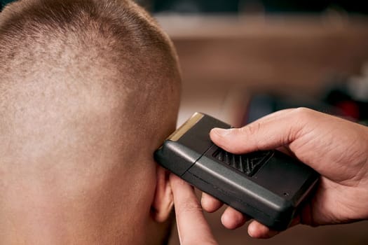 Barber shaving handsome bearded man in barber shop.