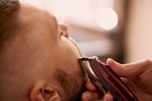 Barber shaving handsome bearded man in barber shop.