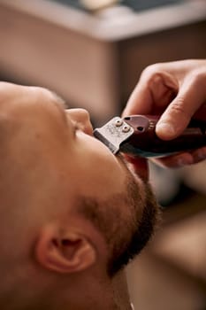 Barber shaving handsome bearded man in barber shop.