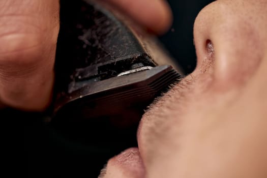 Barber shaving handsome bearded man in barber shop.