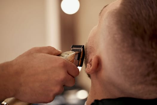 male hands of barber with hair clipper, close up.