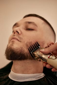 Barber shaving handsome bearded man in barber shop.