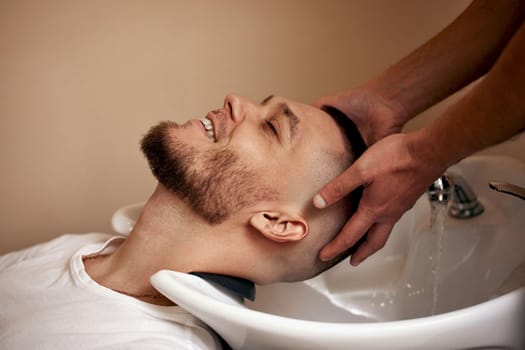 Barber washing hair of caucasian man in barber shop