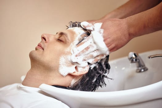 Barber washing hair of caucasian man in barber shop