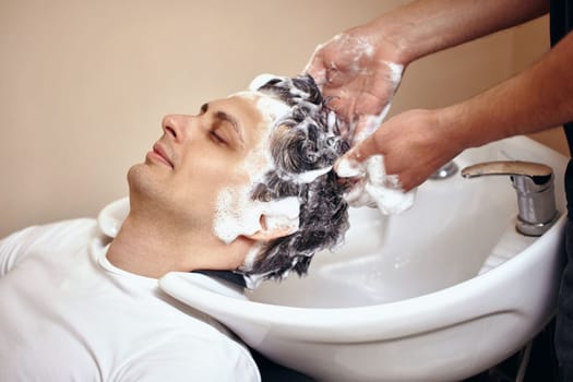 Barber washing hair of caucasian man in barber shop