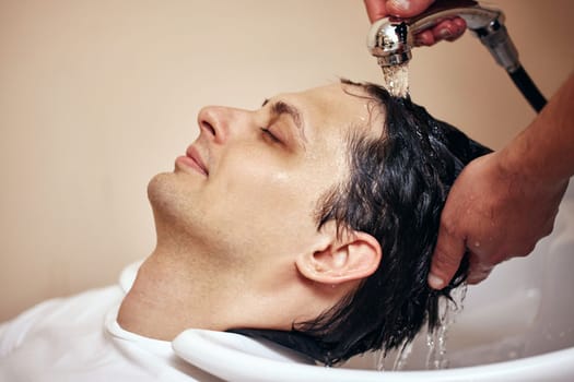 Barber washing hair of caucasian man in barber shop