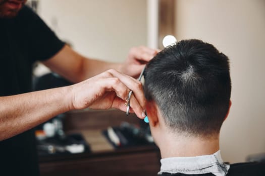 master hairdresser does hairstyle with scissors and comb.