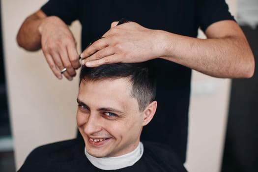 hairdresser does haircut for caucasian man in barber shop
