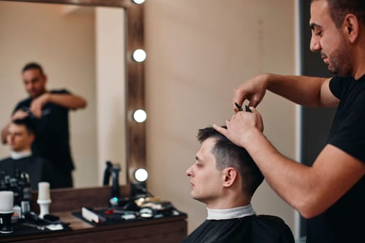 hairdresser does haircut for caucasian man in barber shop. Haircut in the barbershop.