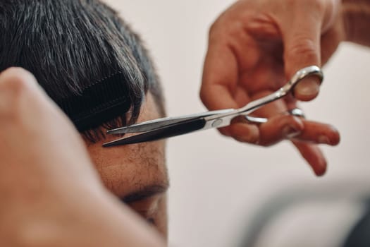 hairdresser does haircut for caucasian man in barber shop. close-up
