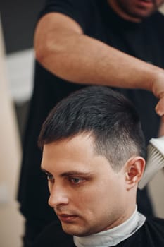 hairdresser does haircut for caucasian man in barber shop