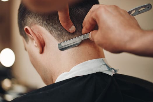 Barber shaving bearded man with razor in barber shop. close-up