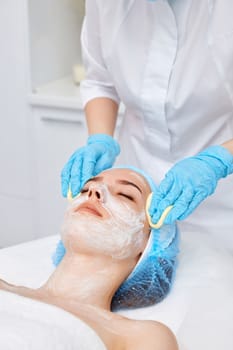 beautician cleanses skin of young woman with sponge. Perfect cleaning, spa treatment skincare face.