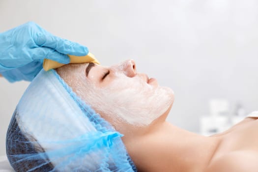 beautician cleanses skin of beautiful woman with sponge. Perfect cleaning, spa treatment skincare face.