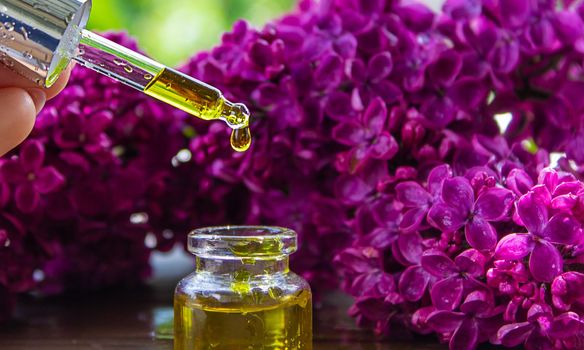 Syringa lilac, essential oil. bottle of beauty oil with lilac flowers. selective focus