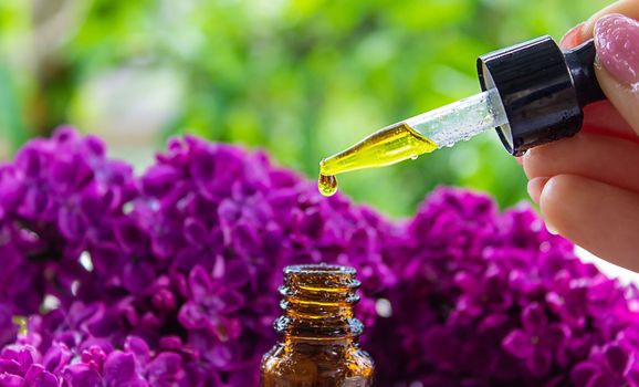 Syringa lilac, essential oil. bottle of beauty oil with lilac flowers. selective focus