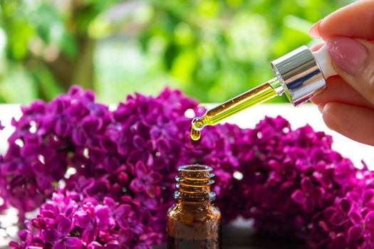 Syringa lilac, essential oil. bottle of beauty oil with lilac flowers. selective focus