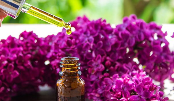 Syringa lilac, essential oil. bottle of beauty oil with lilac flowers. selective focus