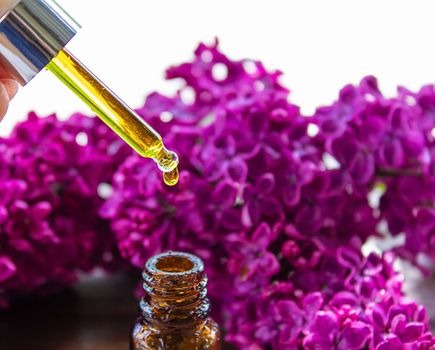 Syringa lilac, essential oil. bottle of beauty oil with lilac flowers. selective focus