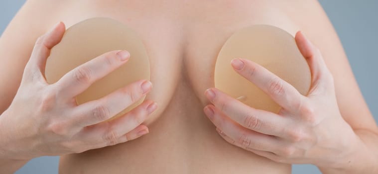 Caucasian naked woman trying on silicone breast implants