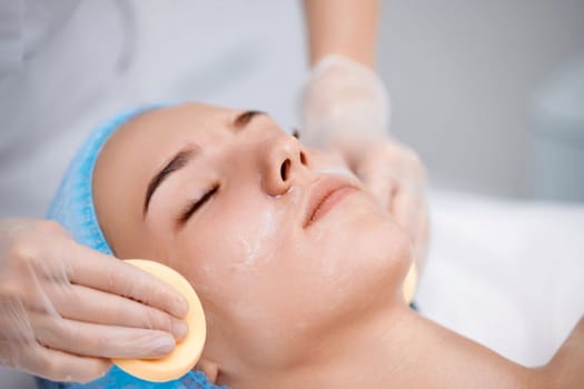 beautician cleanses skin of beautiful woman with sponge. Perfect cleaning, spa treatment skincare face.
