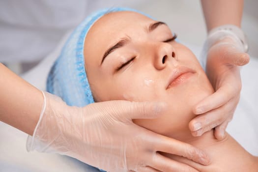 young beautiful woman receiving anti-stress facial massage at spa salon
