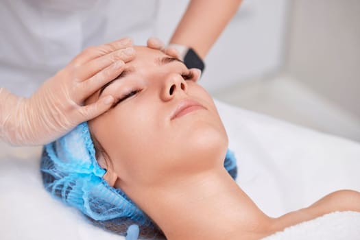young beautiful woman receiving anti-stress facial massage at spa salon