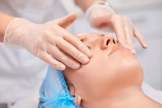 young beautiful woman receiving facial massage at spa salon