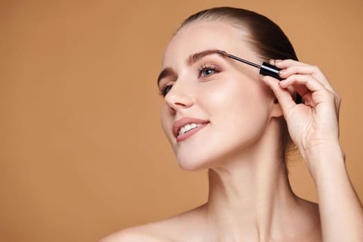 Beautiful happy woman with perfect shape eyebrows on beige background. Natural make up. copy space