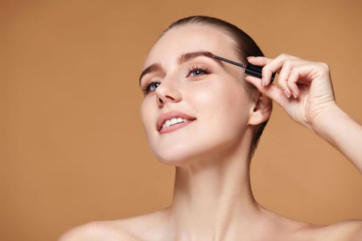 Beautiful woman with perfect shape eyebrows on beige background. Natural make up. copy space