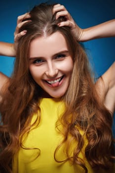 funny woman with strong healthy curly hair dancing on blue background