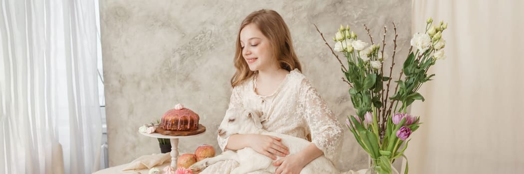 A girl with long hair in a light dress is sitting at the Easter table with cakes, spring flowers and quail eggs. Happy Easter celebration