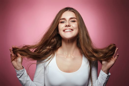 lovely woman with strong healthy curly hair on pink background