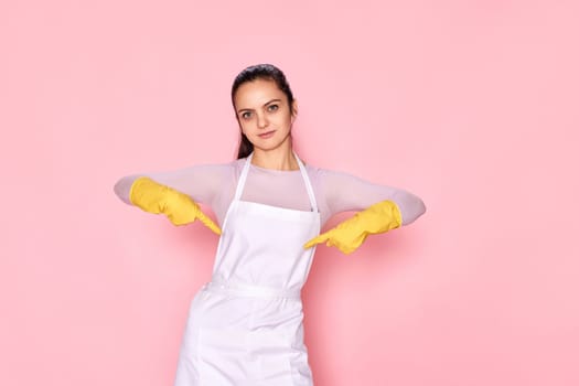 smiling caucasian woman in gloves pointing oneself with fingers on yellow background. cleaning