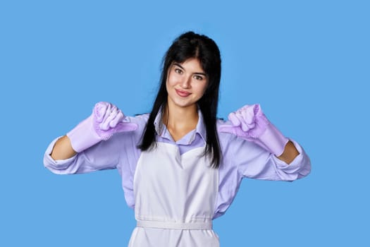 smiling caucasian woman in gloves pointing oneself with fingers isolated on blue background. cleaning
